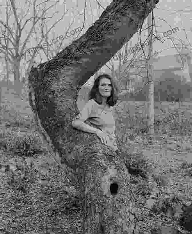 A Photograph Of Jeannette Walls, The Author Of River Could Be Tree, Standing In A Forest. She Is Wearing A Blue Dress And Has Long, Dark Hair. She Is Smiling And Looking At The Camera. A River Could Be A Tree: A Memoir